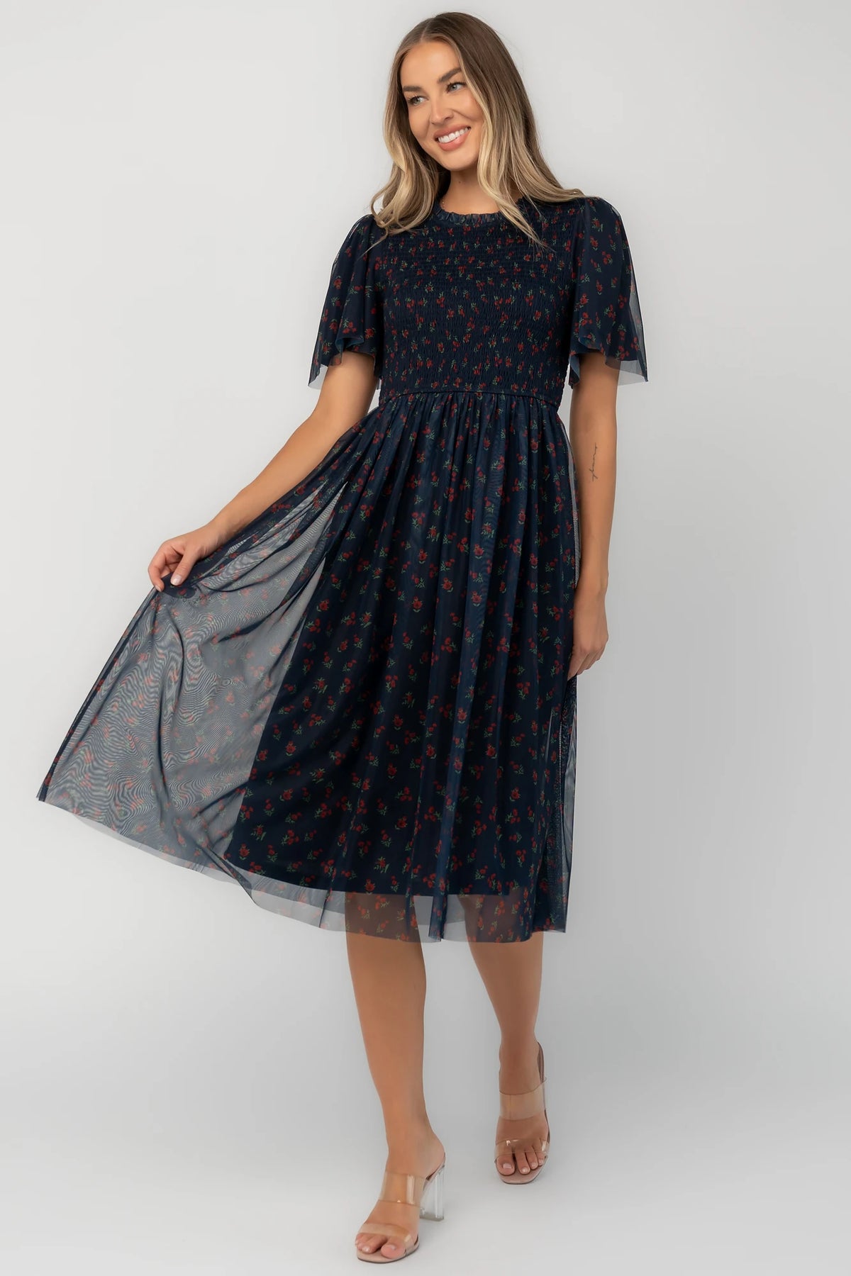 Navy floral mesh midi dress with a high ruffle neckline, flutter sleeves, full smocked bodice, and flowing midi skirt.