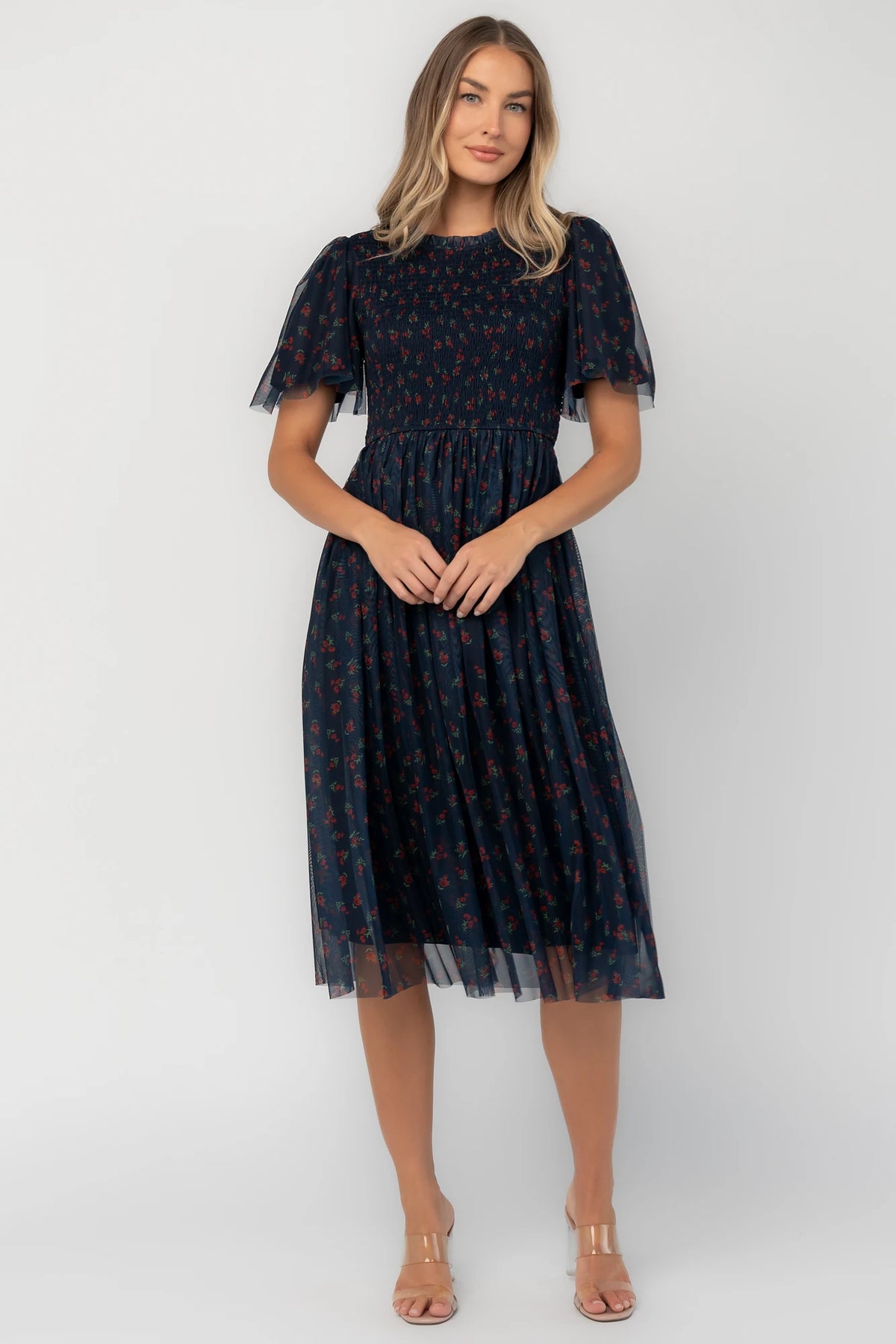 Navy floral mesh midi dress with a high ruffle neckline, flutter sleeves, full smocked bodice, and flowing midi skirt.