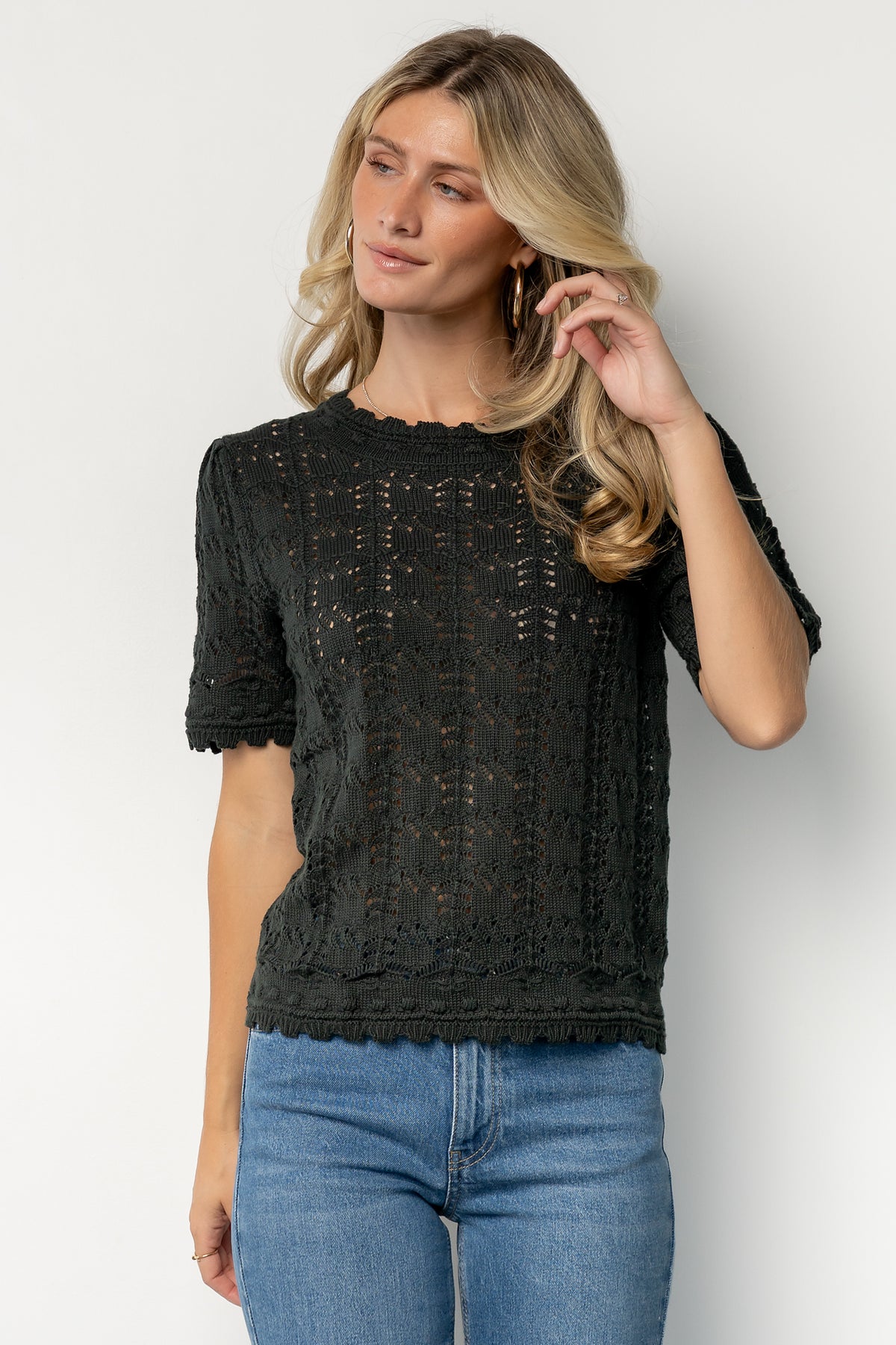 Close-up of open-knit pattern and scalloped trim on the Serenity Knit Sweater Top in deep green, showing stitch detail and texture.