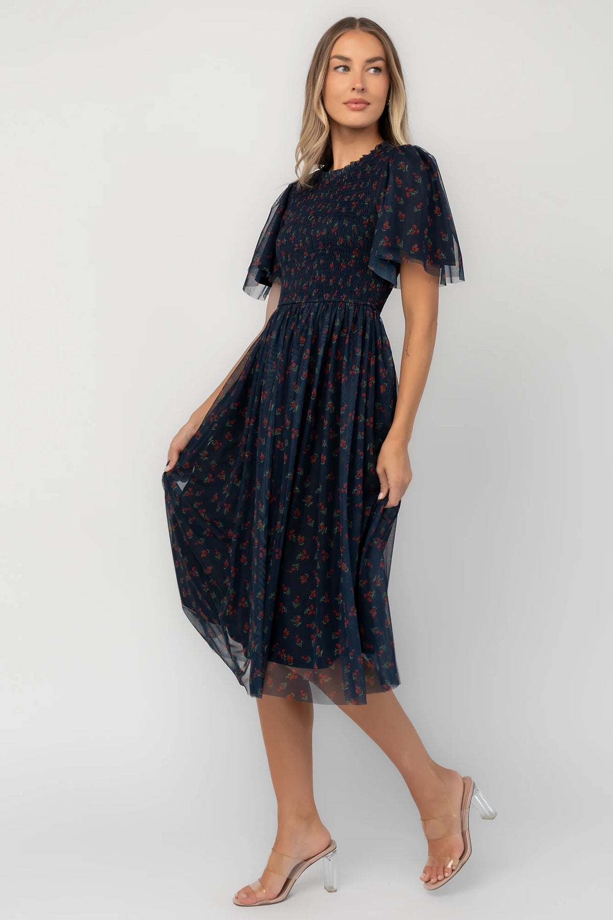Navy floral mesh midi dress with a high ruffle neckline, flutter sleeves, full smocked bodice, and flowing midi skirt.