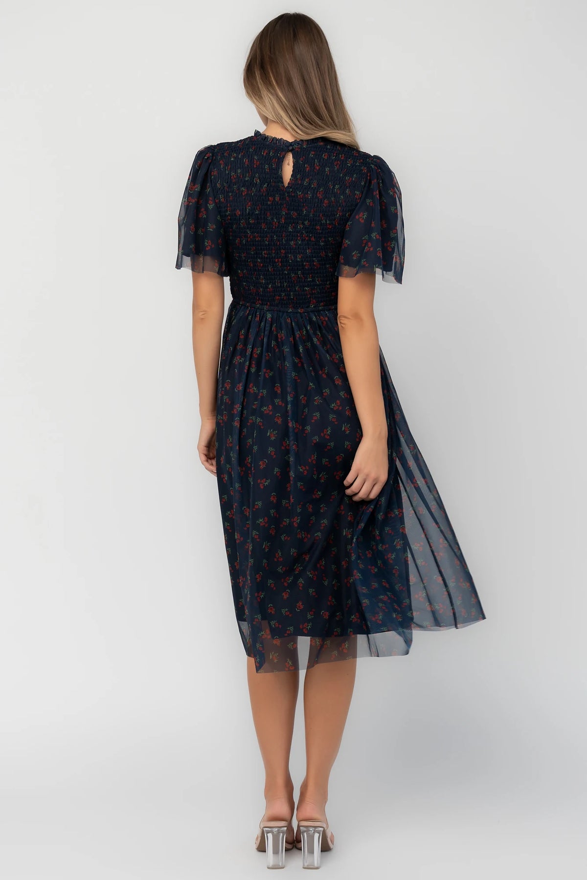 Navy floral mesh midi dress with a high ruffle neckline, flutter sleeves, full smocked bodice, and flowing midi skirt.