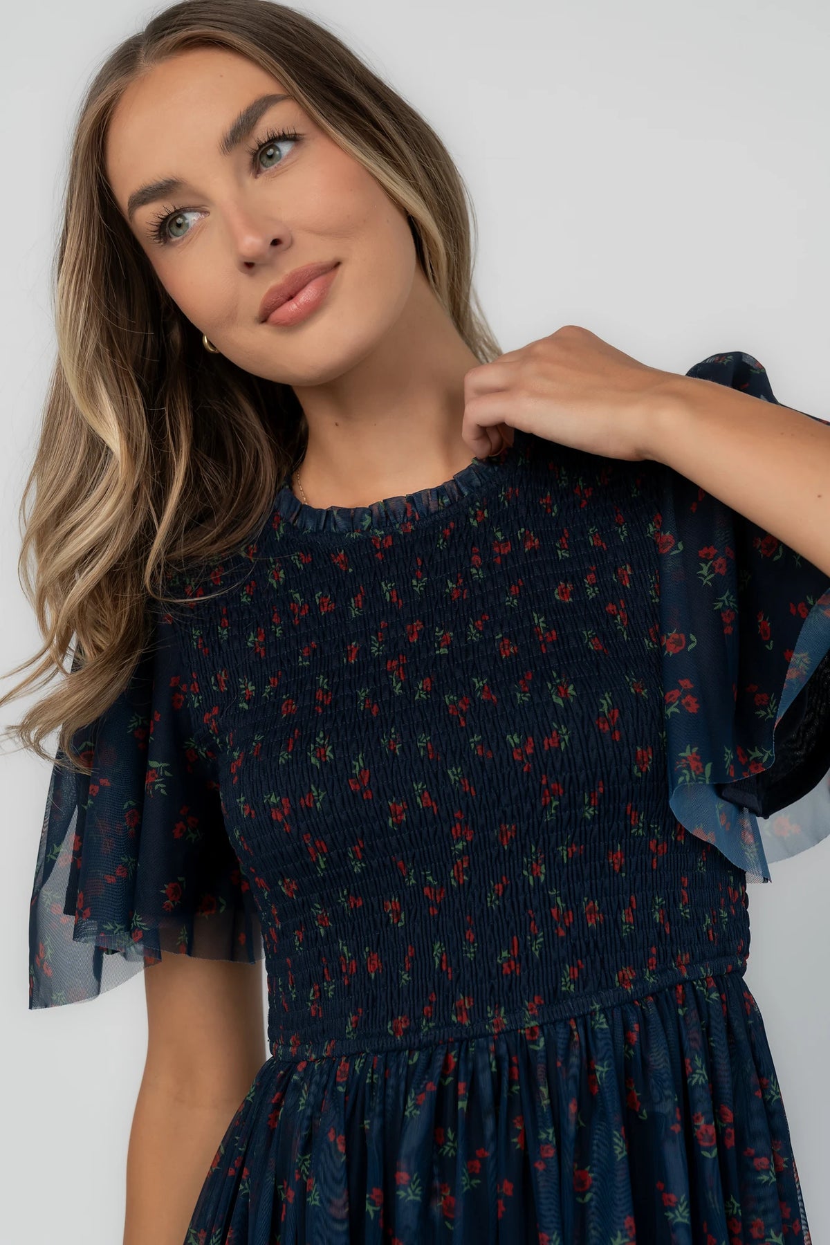 Navy floral mesh midi dress with a high ruffle neckline, flutter sleeves, full smocked bodice, and flowing midi skirt.