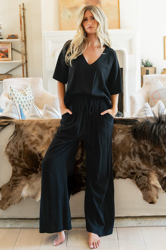 Front view of model wearing Timbre Matching Set in black, V-neck top with side split hem and wide-leg pants.