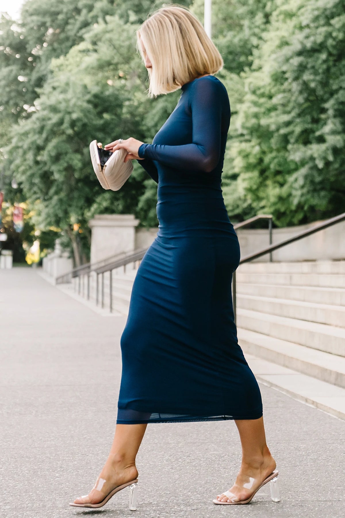 Model wearing the Darya Mesh Midi Dress in Navy featuring a sheer mesh overlay with a round neckline, long sleeves, and a fitted bodycon midi silhouette layered over a matching ribbed slip.