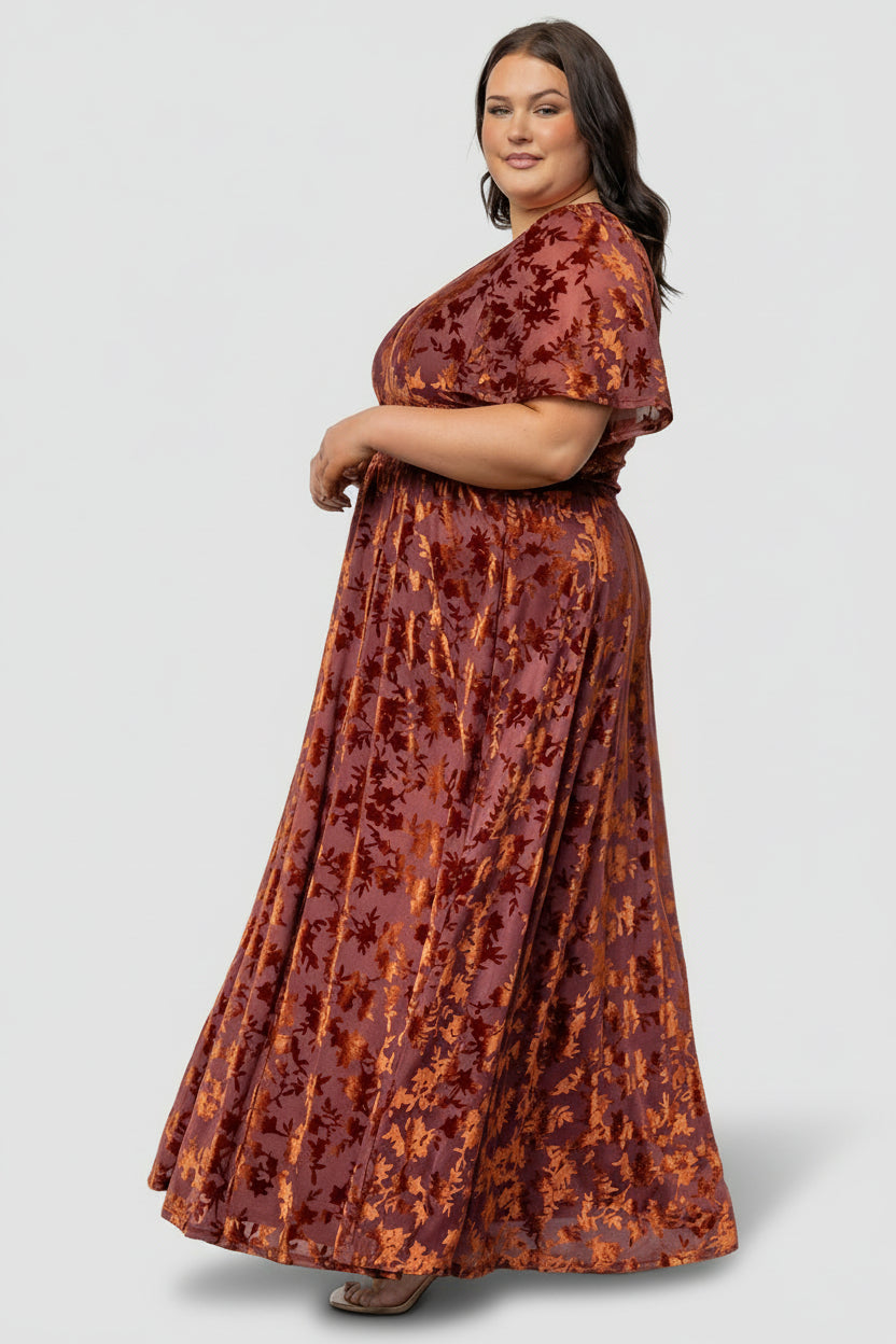 Three-quarter view of Veronica velvet maxi dress in rust on model, showing fit through bodice and skirt drape.
