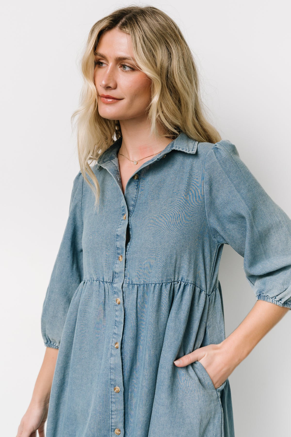Close-up of acid-washed chambray fabric and gathered shoulder detail, highlighting the elastic cuff on the 3/4 sleeve.