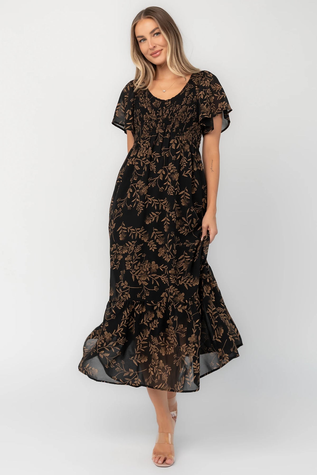 Black and gold chiffon maxi dress with a V-neckline, flutter sleeves, smocked bodice, empire waist, tiered skirt, and side pockets.