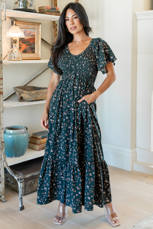 Full-length image of the Jerah smocked midi dress in deep jade floral on a model, showing V-neck, smocked bodice, and skirt movement.