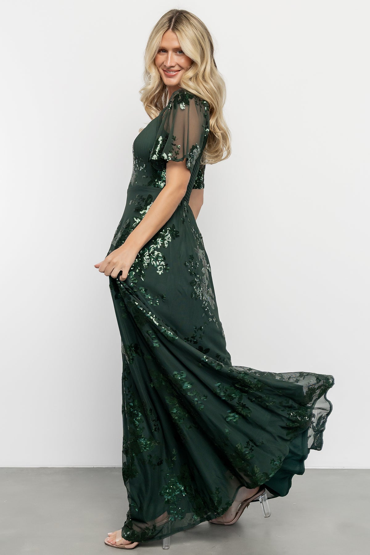 Three-quarter side view of the Karina sequin maxi dress on model, highlighting princess seams, mesh drape, and elegant skirt movement.