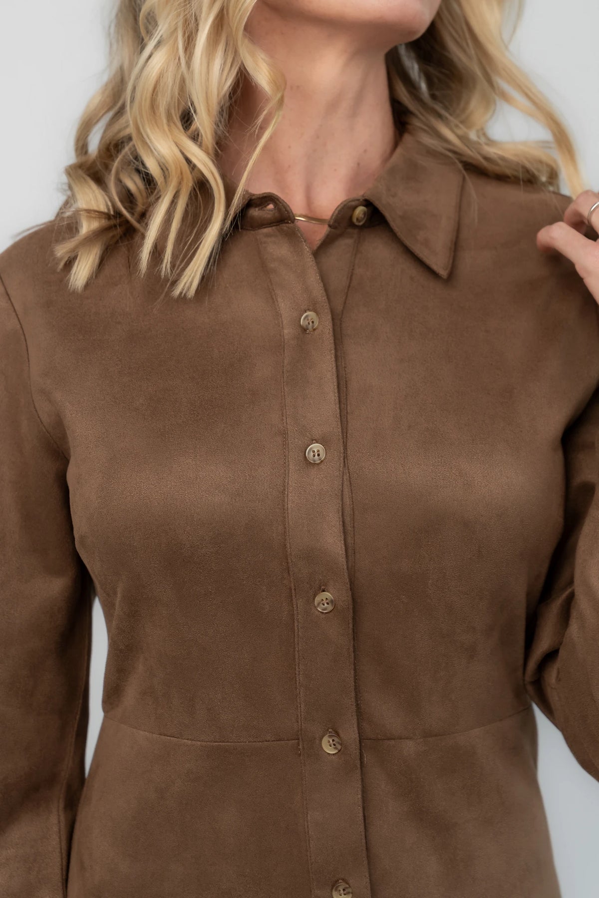 Coffee faux suede mini dress with a collared neckline, button-front closure, long sleeves, fitted waist, and pleated skirt.