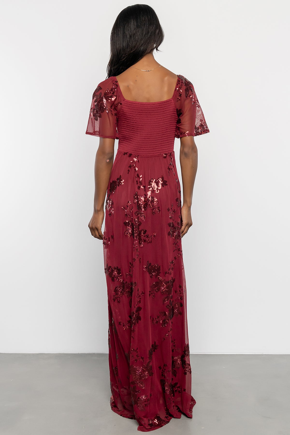 Side profile of Karina sequin maxi dress in wine showing skirt drape and elastic at back waist for fitted silhouette.