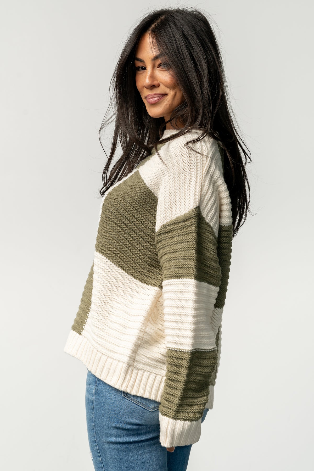 Model styling shot of Jayda cream and olive sweater paired with casual bottoms, displaying overall fit and how the pattern reads at a distance.