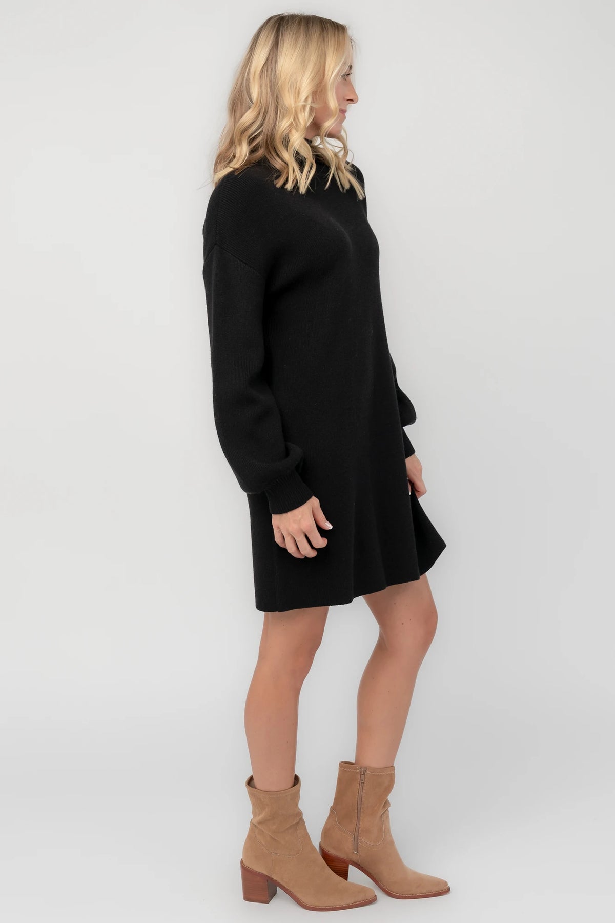 Black knit sweater dress with a mock neckline, long balloon sleeves, dropped shoulders, and a relaxed above-the-knee silhouette.