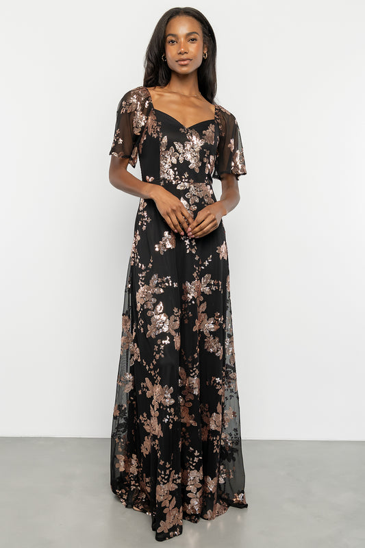 Front view of black and gold sequin maxi dress on model, showing sweetheart neckline, floral sequin pattern and flowing skirt movement.