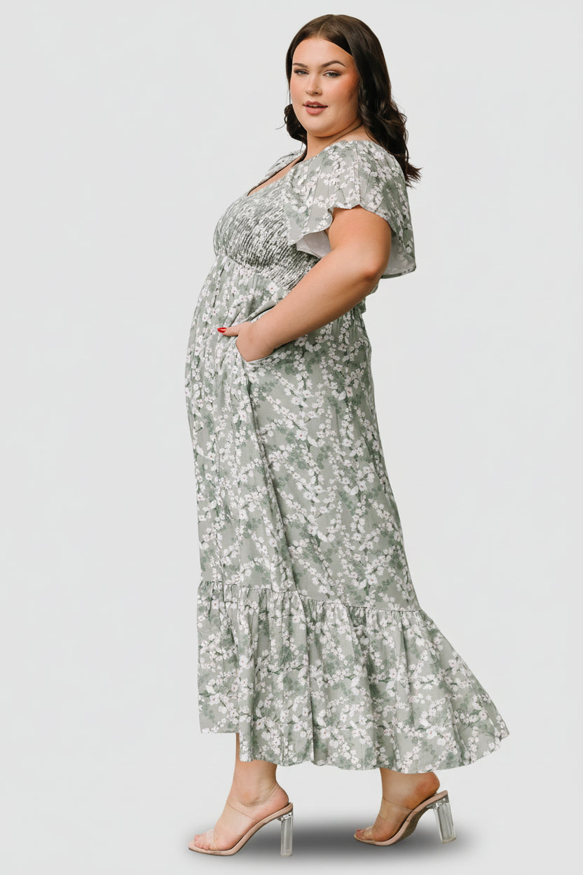 Model wearing the Joanie Smocked Midi Dress while pregnant, demonstrating the bump-friendly empire waist and comfortable length.
