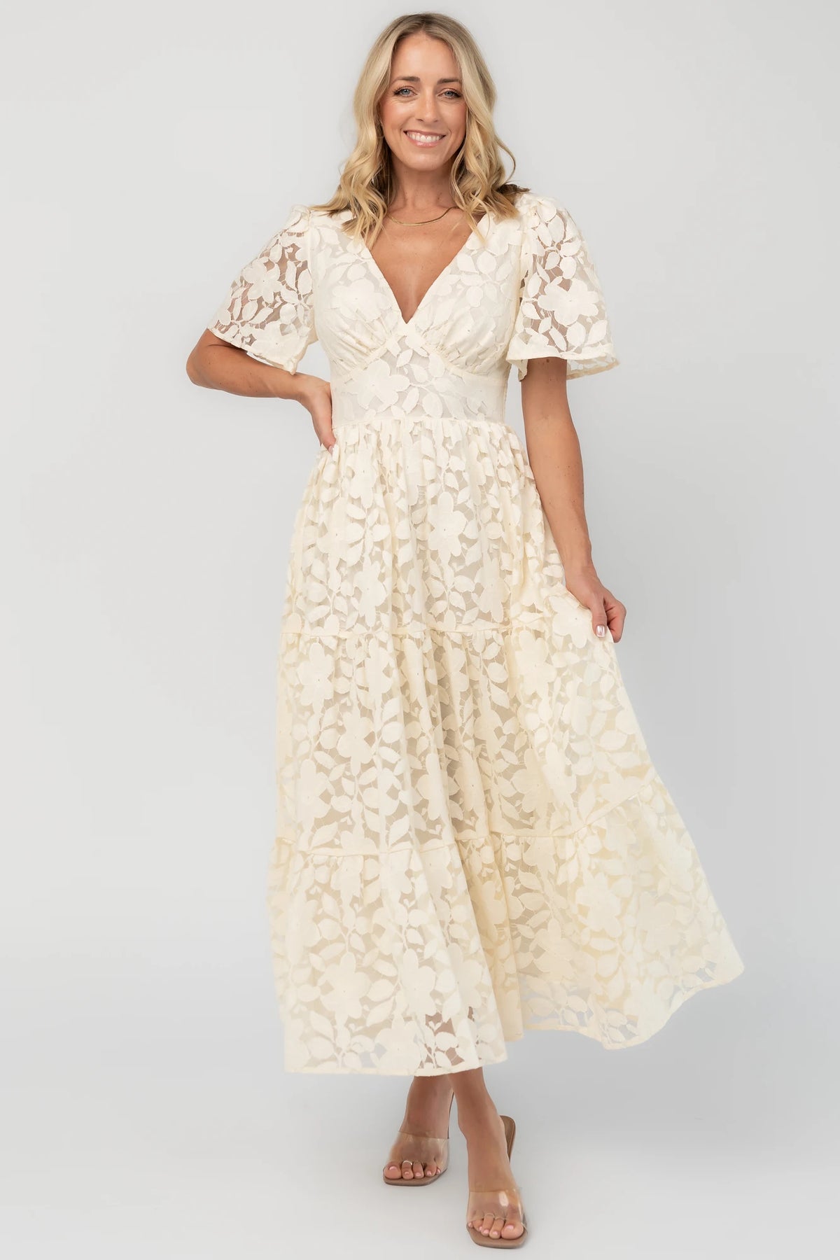 Floral lace midi dress with a deep V-neckline, short flutter sleeves, smocked back bodice, defined waistband, and tiered skirt.