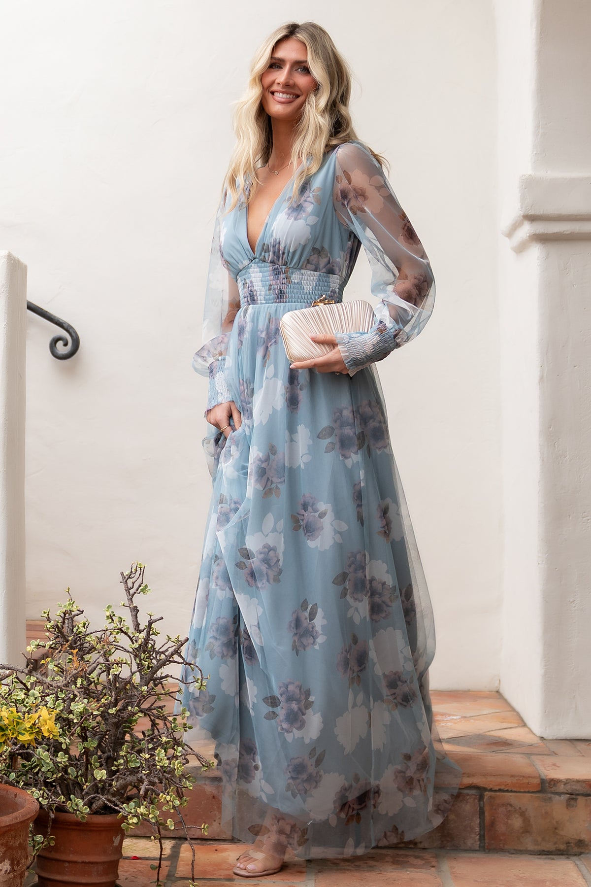 Model walking in Layla light blue floral maxi dress, illustrating the dress’s fluid movement, sheer sleeves, and elegant drape of the tulle overlay.