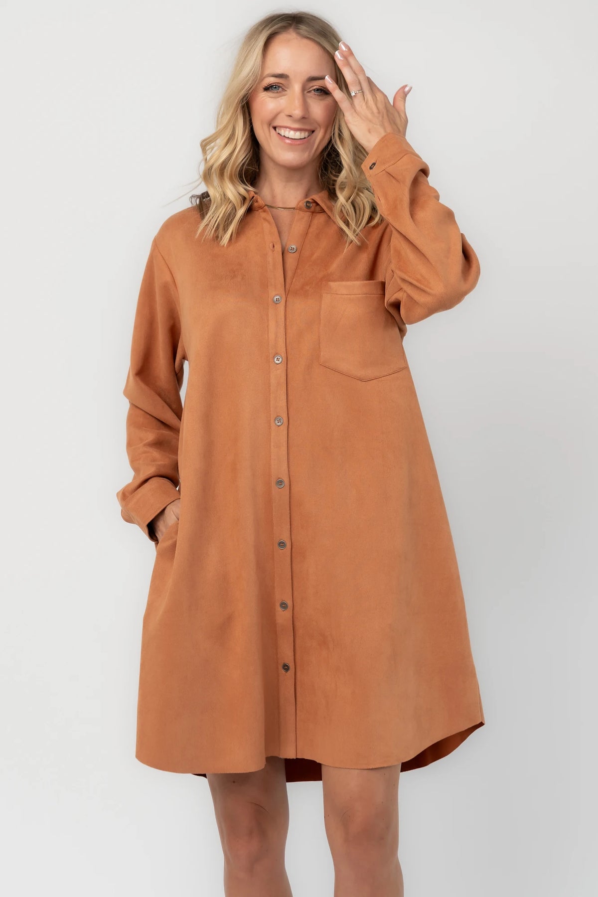 Camel faux suede shirt dress with a collared neckline, button-front closure, front patch pocket, long sleeves, and a relaxed oversized silhouette.