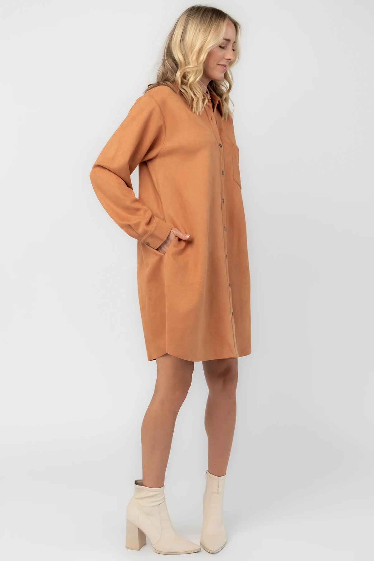 Camel faux suede shirt dress with a collared neckline, button-front closure, front patch pocket, long sleeves, and a relaxed oversized silhouette.