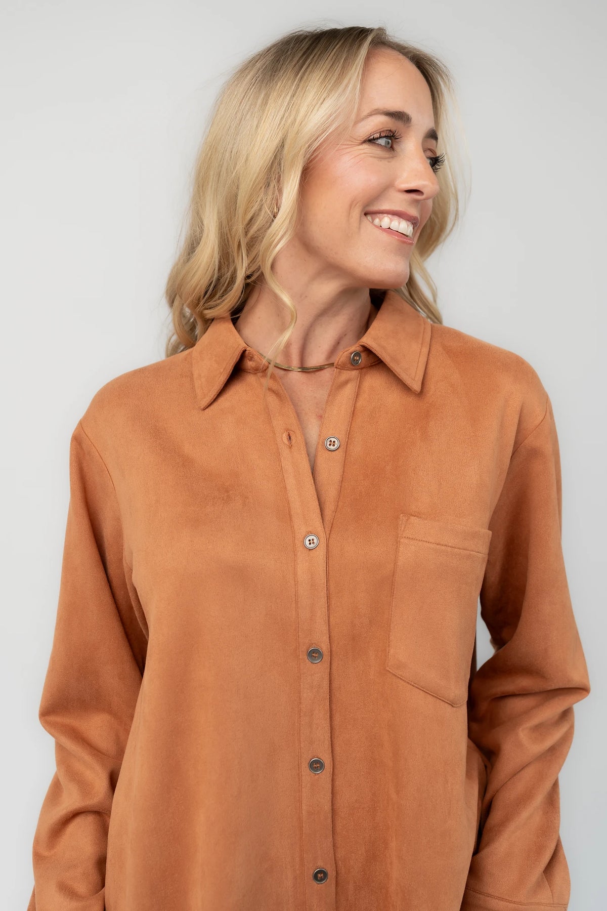 Camel faux suede shirt dress with a collared neckline, button-front closure, front patch pocket, long sleeves, and a relaxed oversized silhouette.