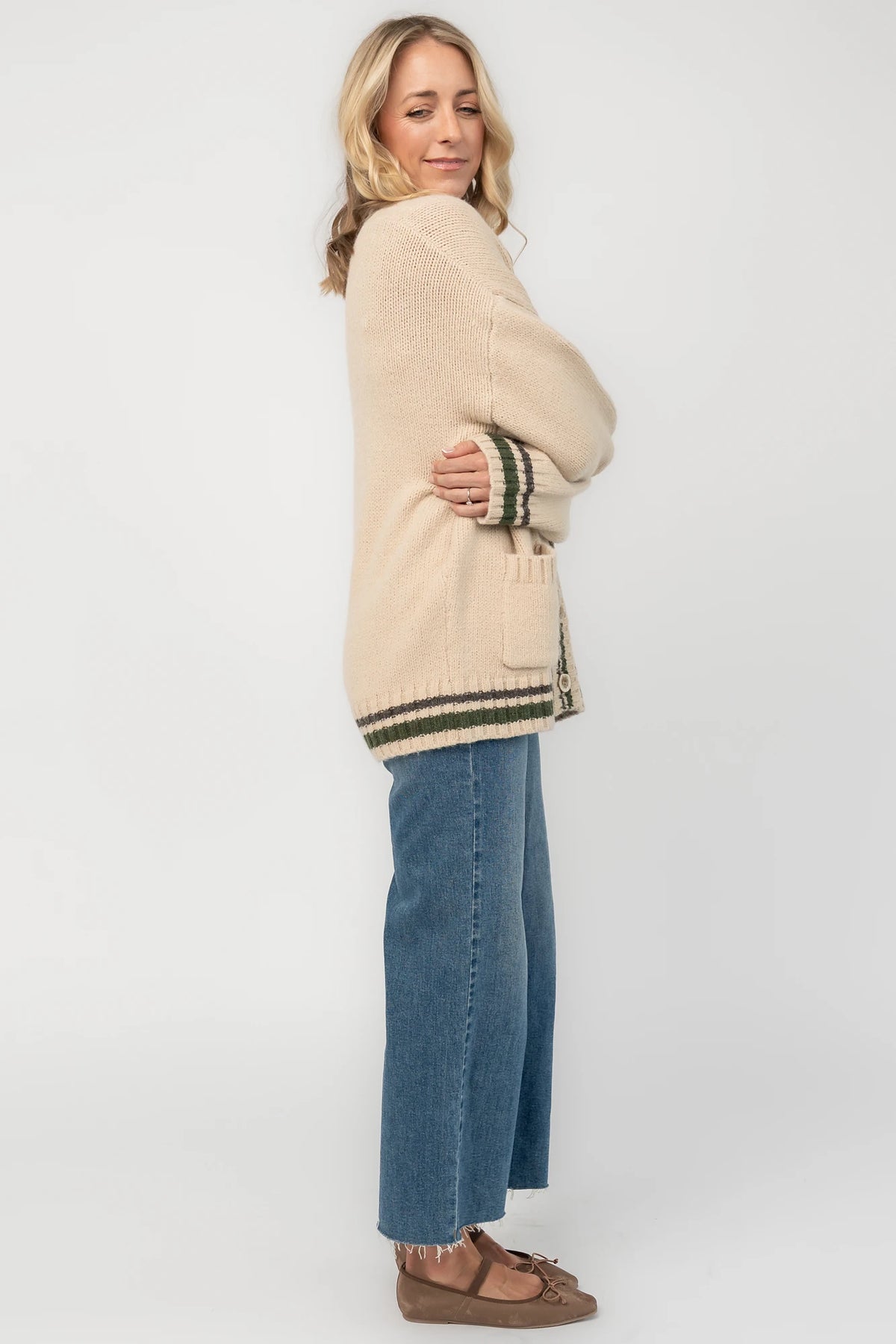 Oatmeal knit cardigan with a V-neckline, button-front closure, olive and charcoal striped trim, front patch pockets, and a relaxed fit.