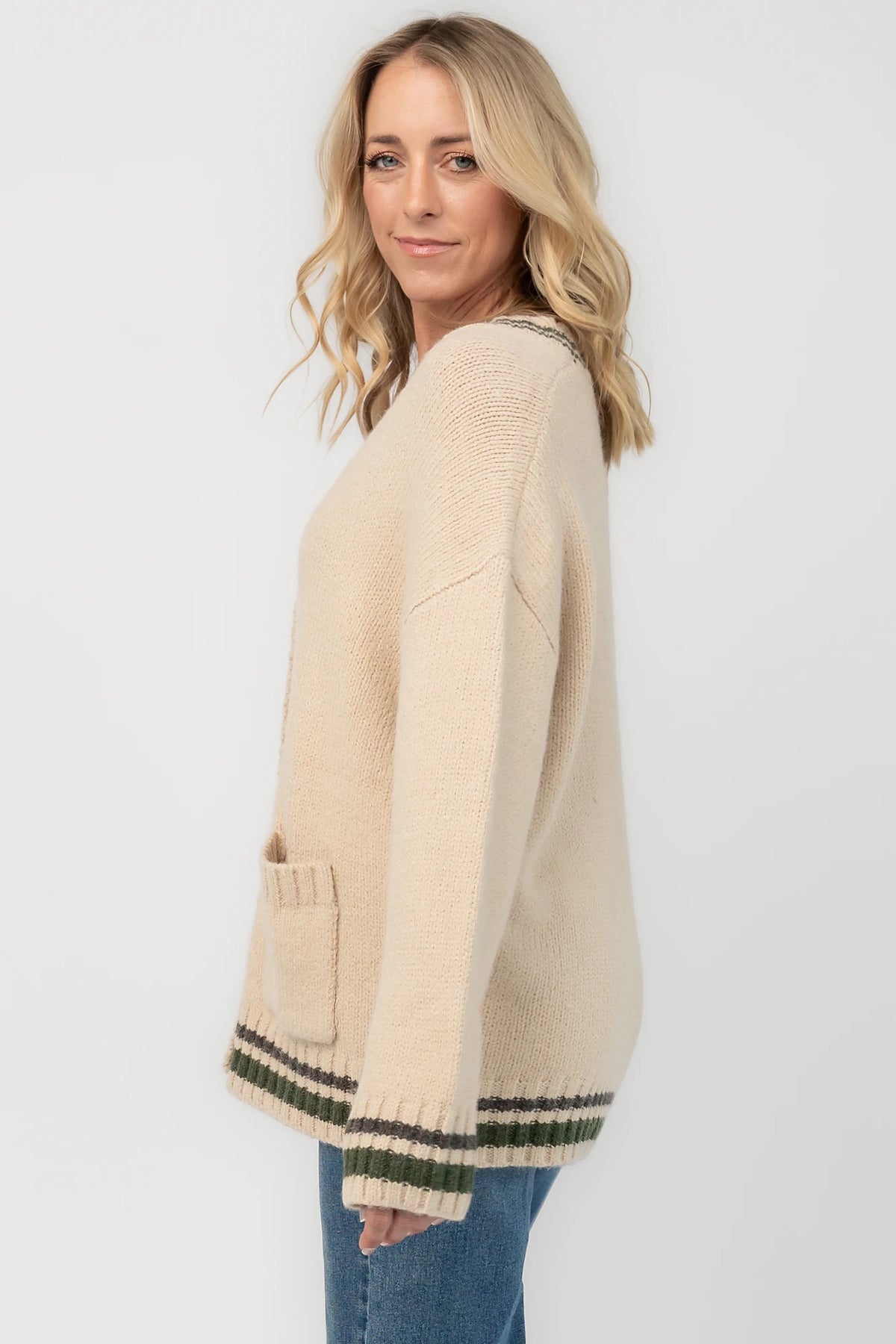 Oatmeal knit cardigan with a V-neckline, button-front closure, olive and charcoal striped trim, front patch pockets, and a relaxed fit.