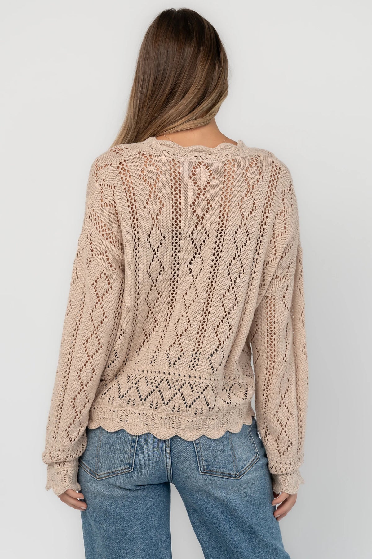 Oatmeal pointelle knit sweater with a scalloped henley neckline, functional button front, dropped shoulders, long sleeves, and a scalloped hem.