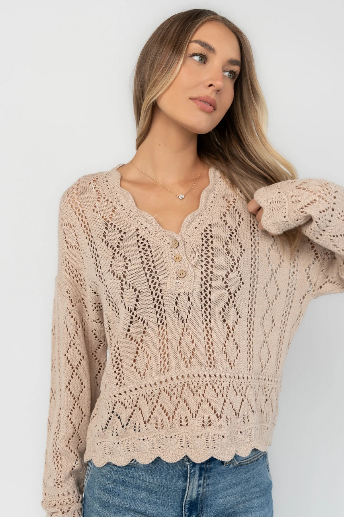 Oatmeal pointelle knit sweater with a scalloped henley neckline, functional button front, dropped shoulders, long sleeves, and a scalloped hem.