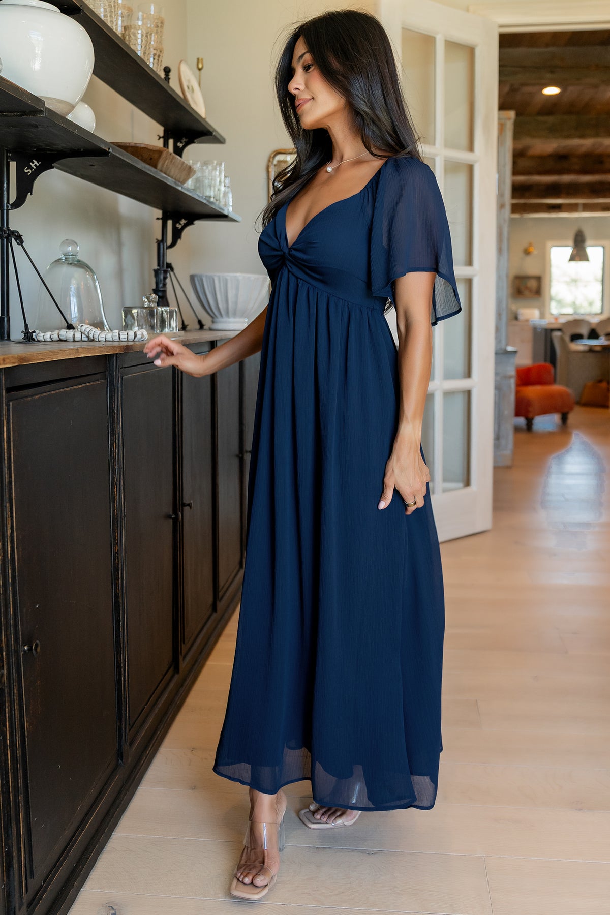Side-angle shot of the navy Nora Midi Dress showing short flutter sleeve with elastic cuff and soft drape through the skirt.