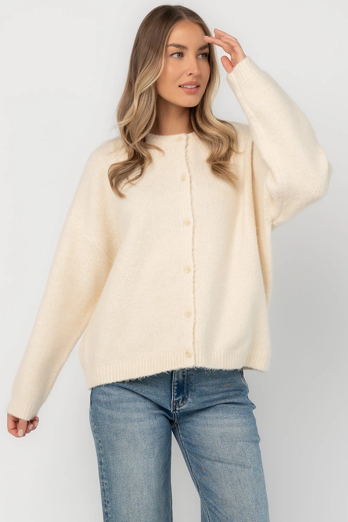 Cream fuzzy knit cardigan with a round neckline, button-front closure, long sleeves, dropped shoulders, and a relaxed fit.