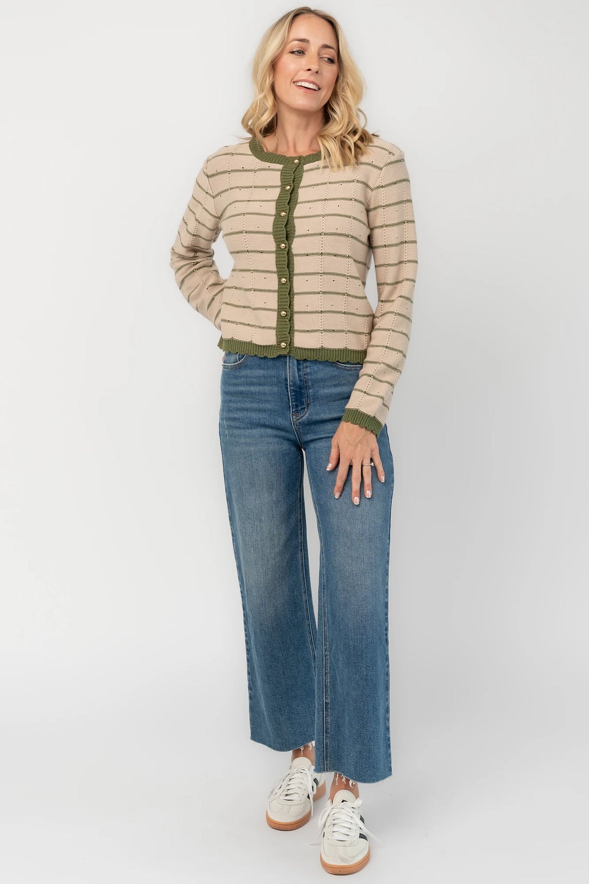 Beige pointelle knit cardigan with olive striped detailing, a round scalloped neckline, pearl-inspired button-front closure, long sleeves, and scalloped ribbed trim.