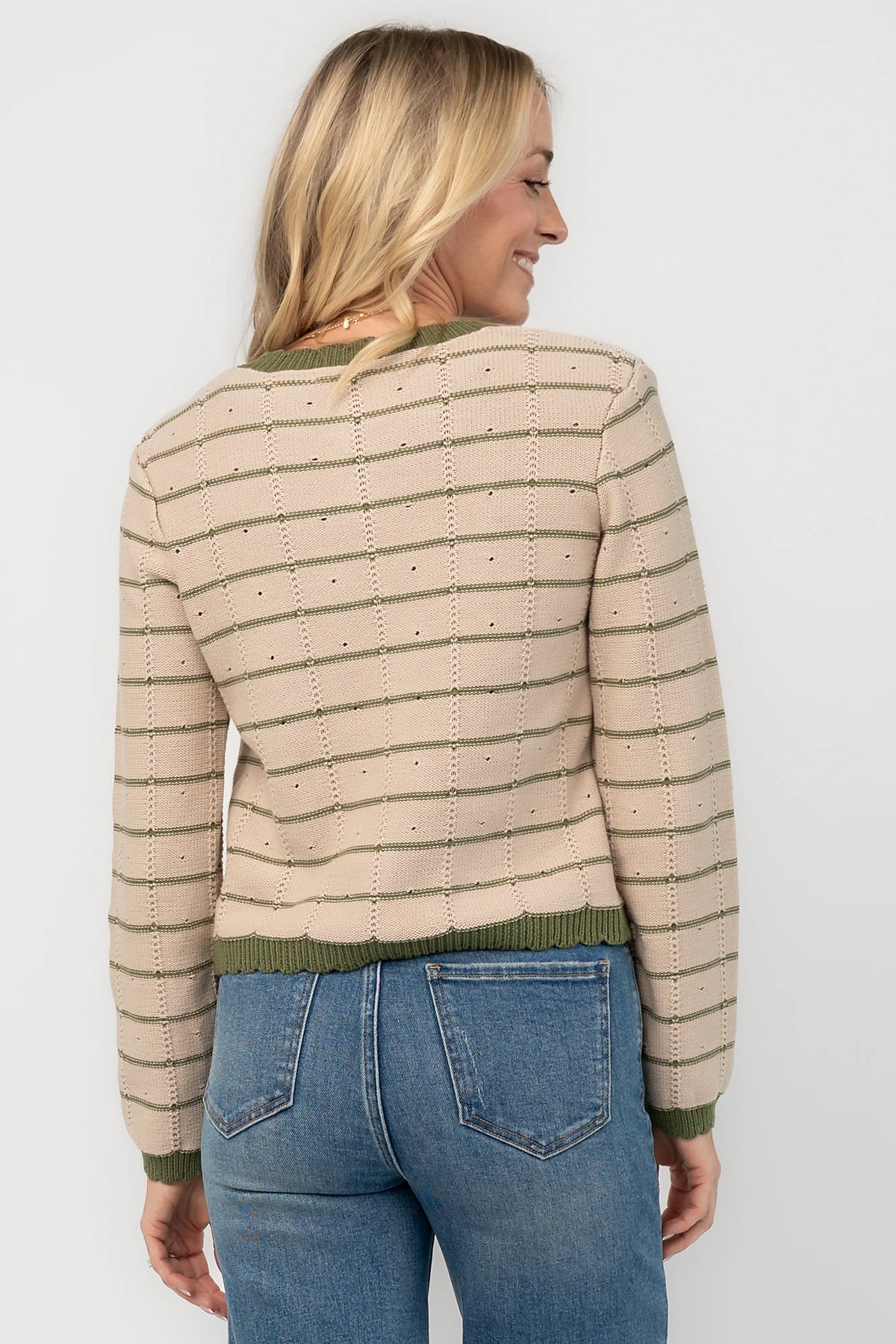Beige pointelle knit cardigan with olive striped detailing, a round scalloped neckline, pearl-inspired button-front closure, long sleeves, and scalloped ribbed trim.