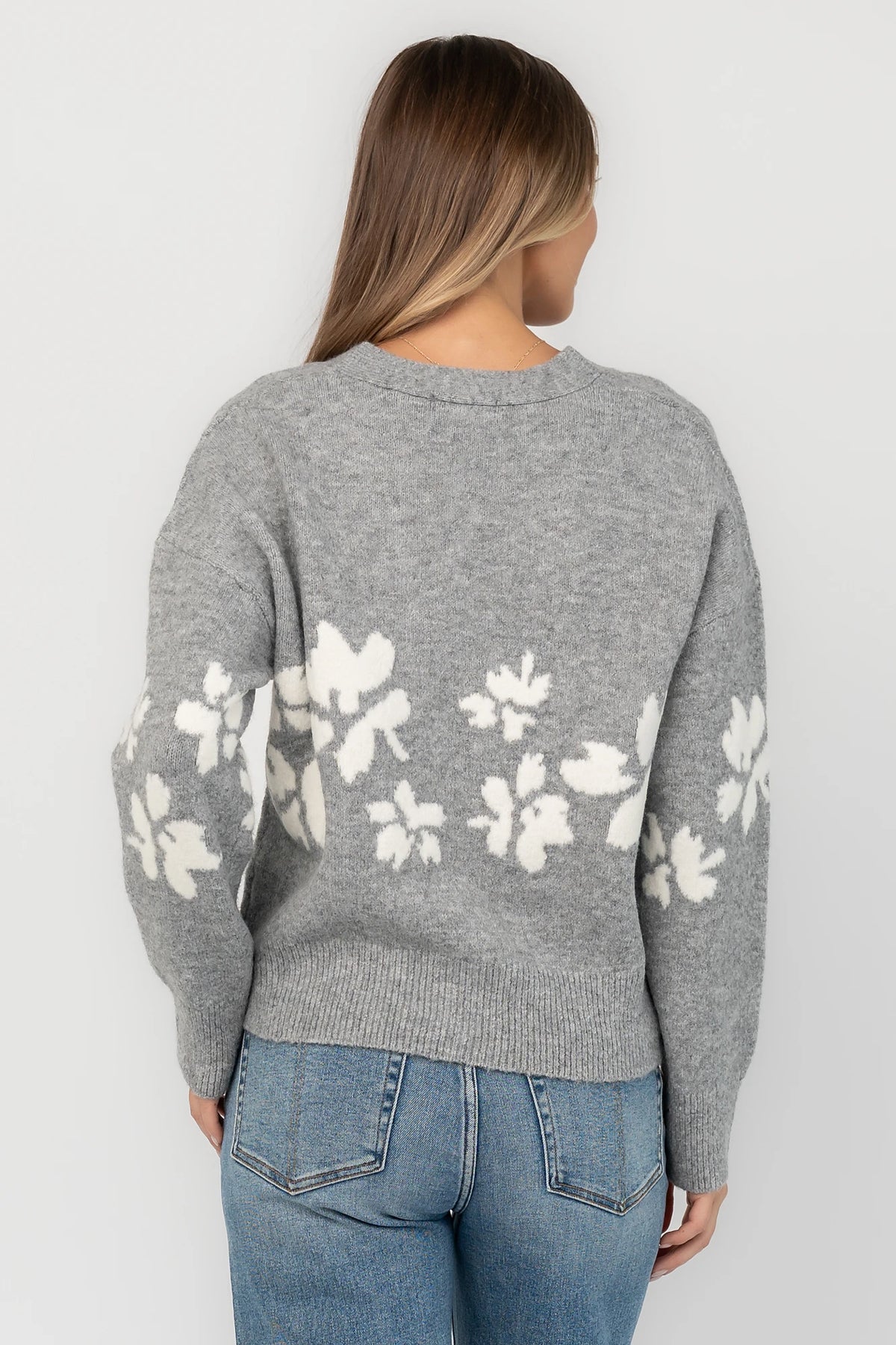 Gray floral knit cardigan with a V-neckline, button-front closure, long sleeves, ribbed trim, and a relaxed silhouette.