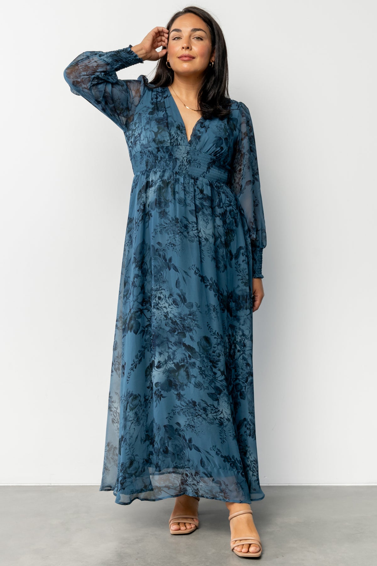 Close-up of deep blue floral chiffon fabric and smocked cuff detail on long sleeve, showing texture and print.