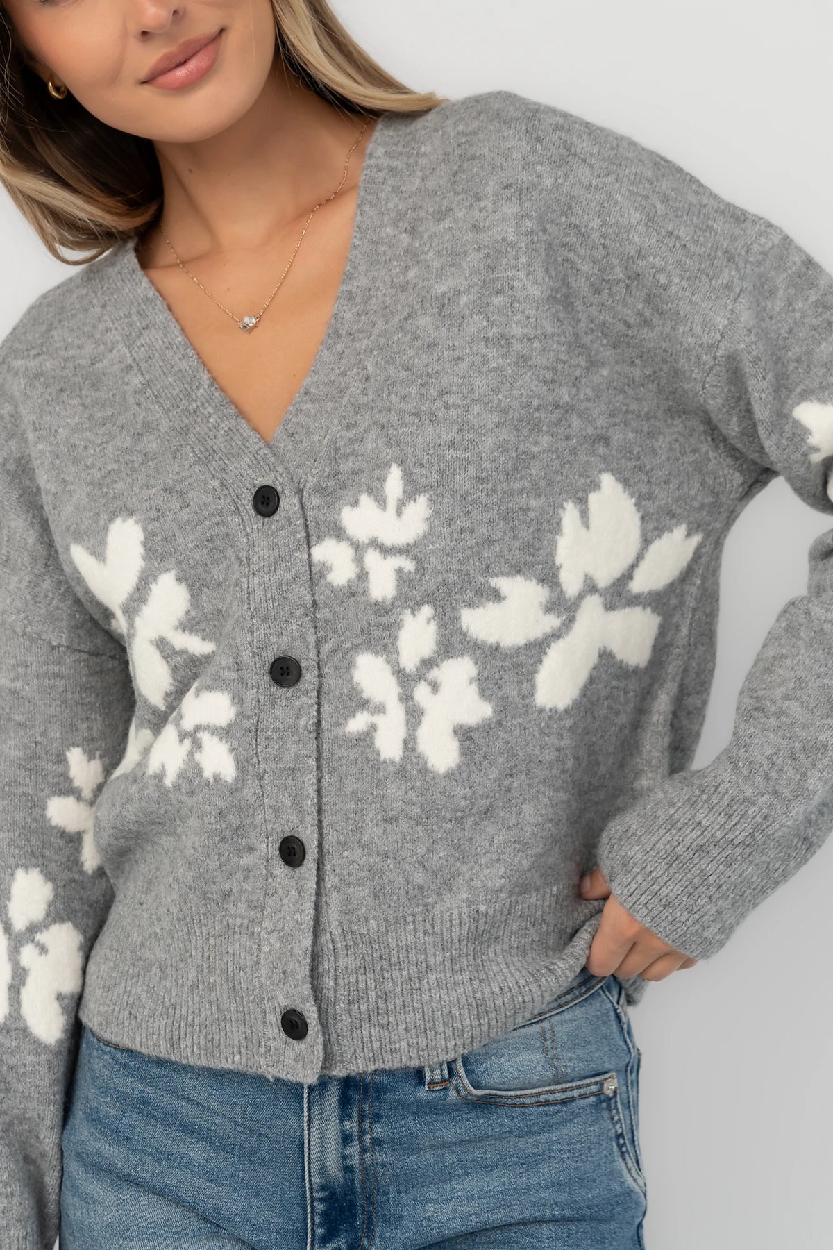 Gray floral knit cardigan with a V-neckline, button-front closure, long sleeves, ribbed trim, and a relaxed silhouette.