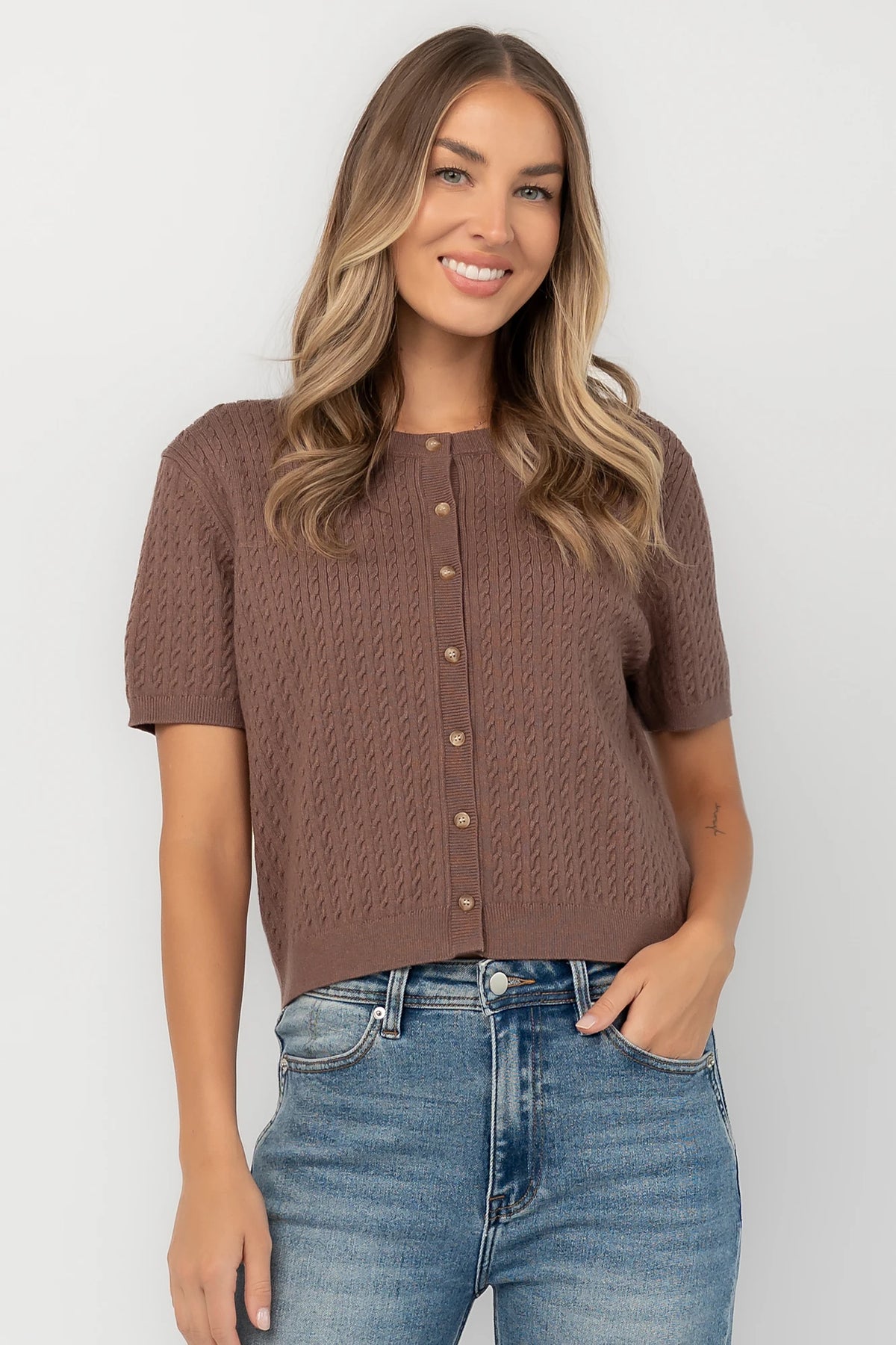 Brown cable knit cardigan with a round neckline, short sleeves, button-front closure, ribbed trim, and a relaxed fit.