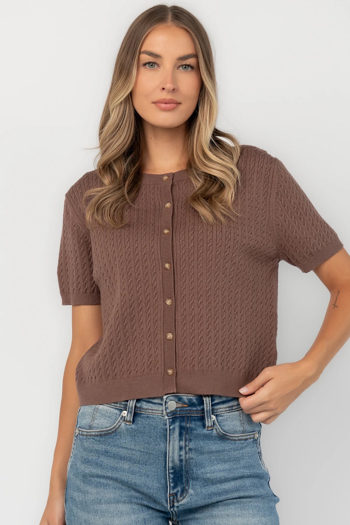 Brown cable knit cardigan with a round neckline, short sleeves, button-front closure, ribbed trim, and a relaxed fit.