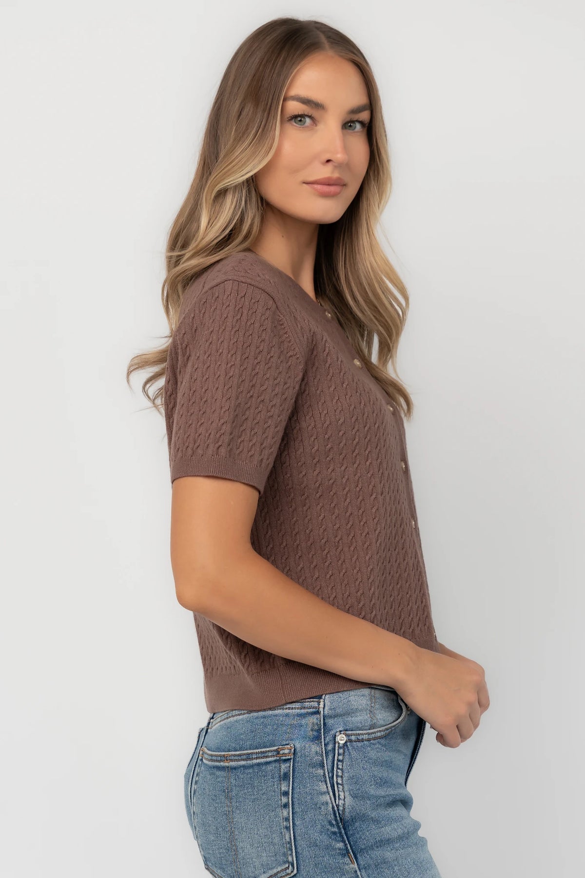 Brown cable knit cardigan with a round neckline, short sleeves, button-front closure, ribbed trim, and a relaxed fit.
