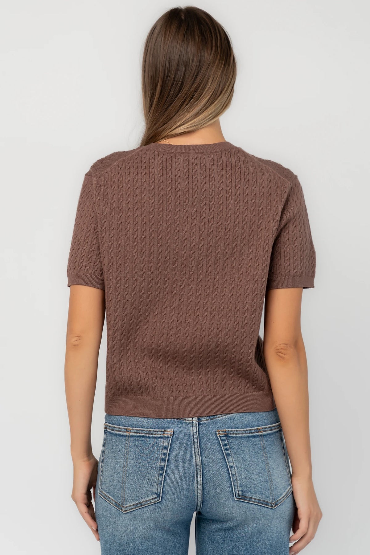 Brown cable knit cardigan with a round neckline, short sleeves, button-front closure, ribbed trim, and a relaxed fit.