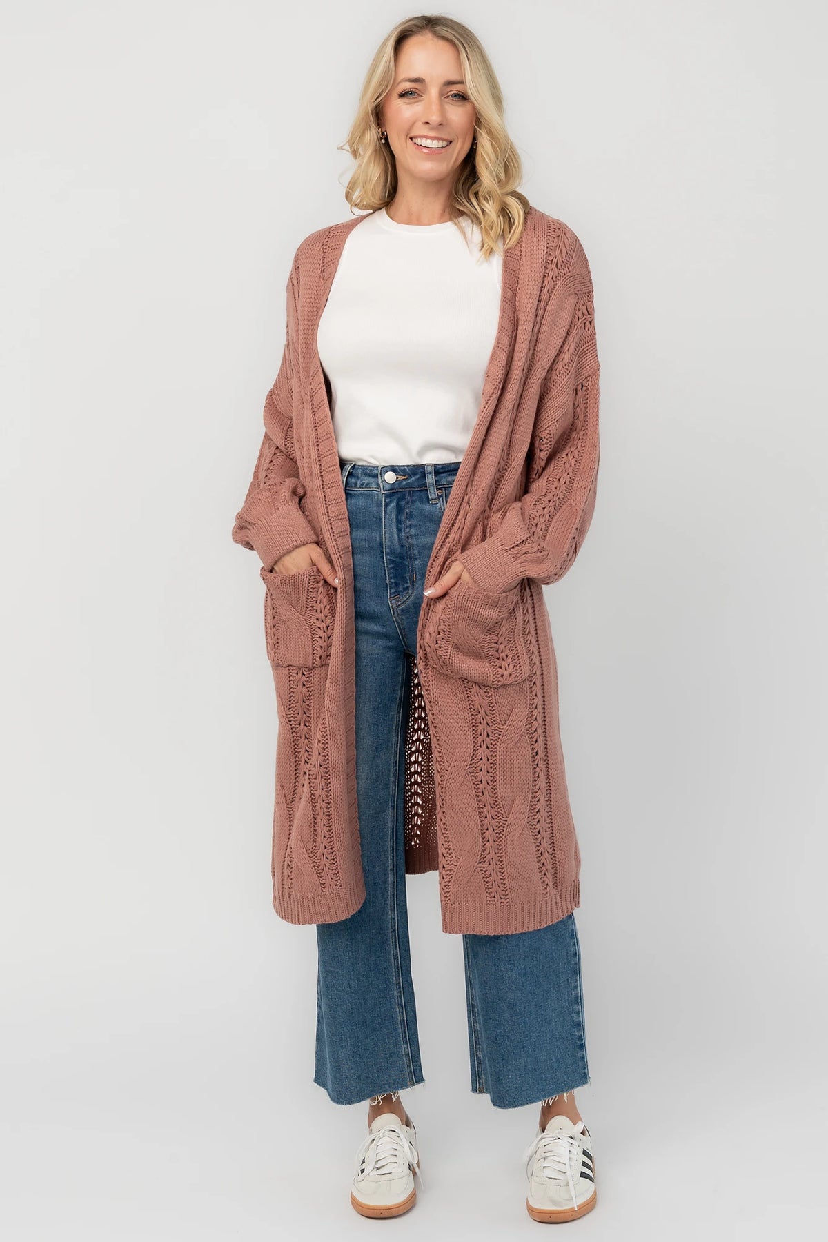 Dusty rosewood cable knit cardigan with an open front, long balloon sleeves, front patch pockets, and a relaxed longline silhouette.