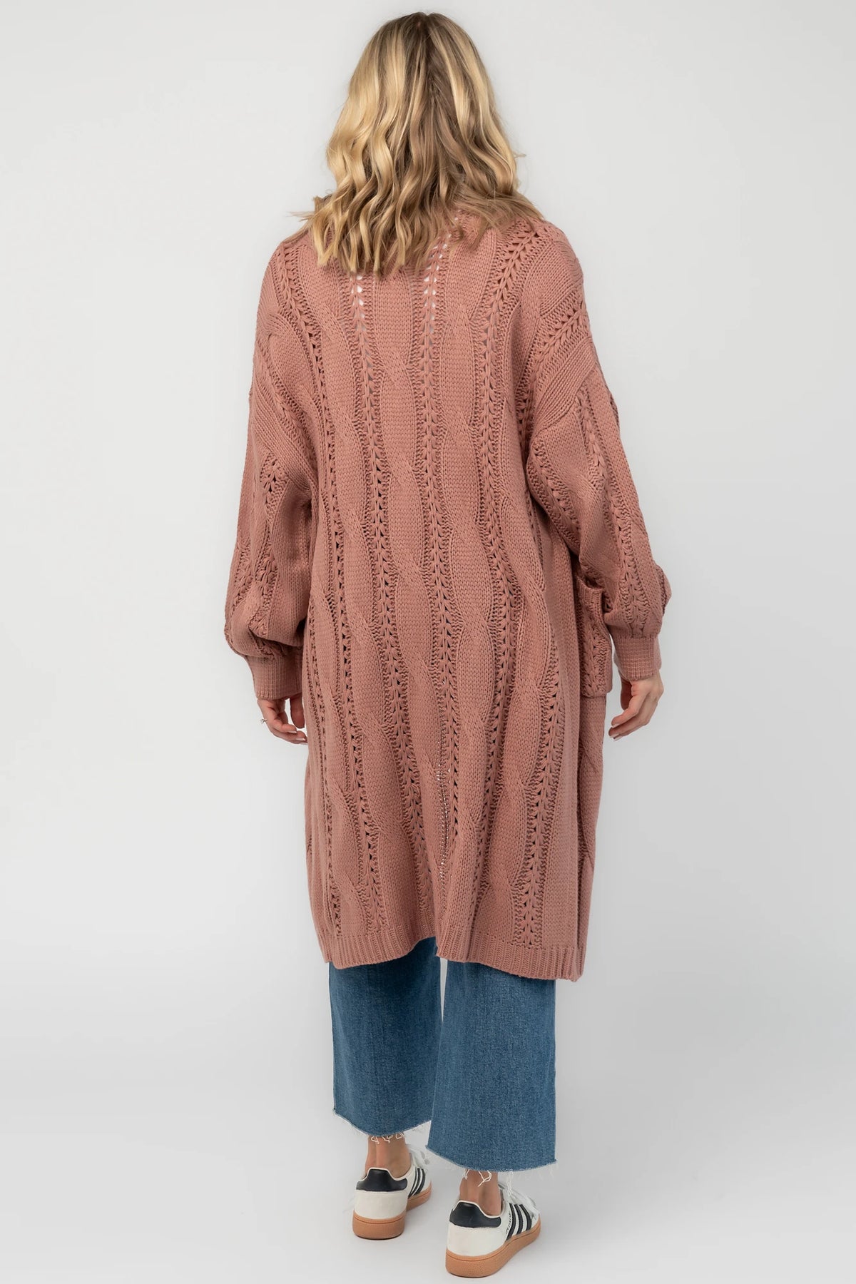 Dusty rosewood cable knit cardigan with an open front, long balloon sleeves, front patch pockets, and a relaxed longline silhouette.
