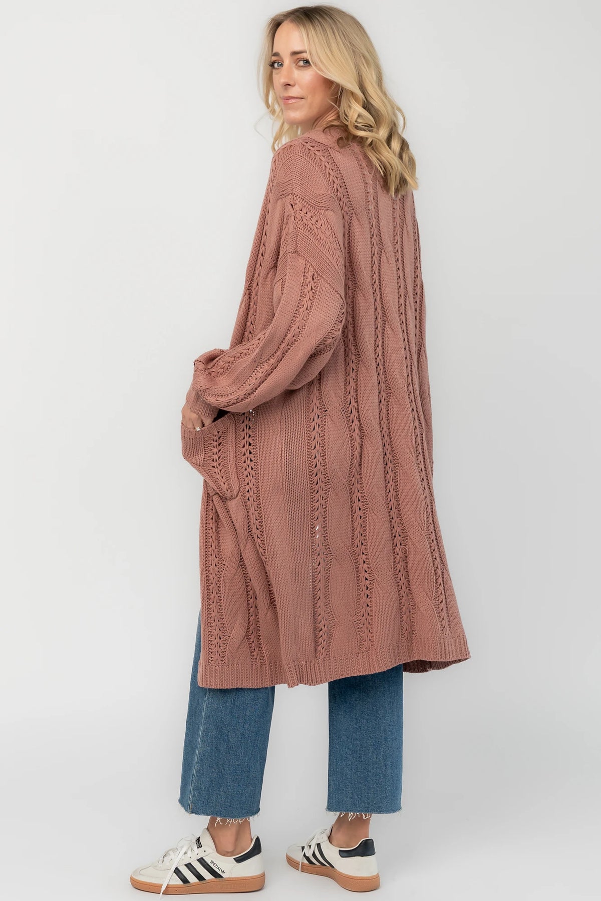 Dusty rosewood cable knit cardigan with an open front, long balloon sleeves, front patch pockets, and a relaxed longline silhouette.
