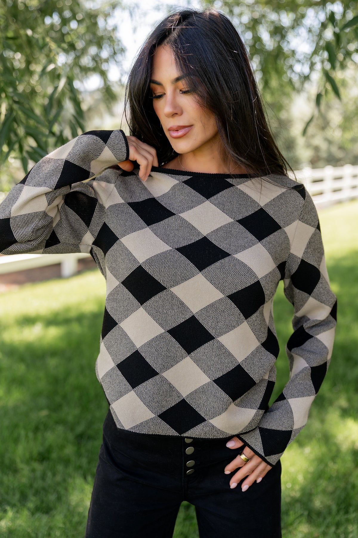 Close-up detail of the black and natural argyle knit showing texture, stitch definition, and the soft sweater yarn composition.