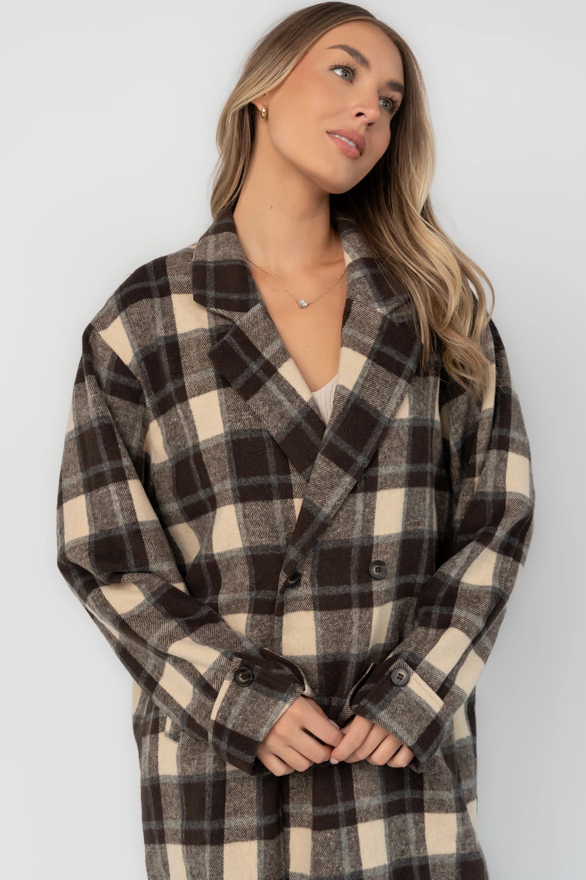 Brown plaid double-breasted longline coat with a collared lapel neckline, side pockets, back slit, and relaxed tailored fit.