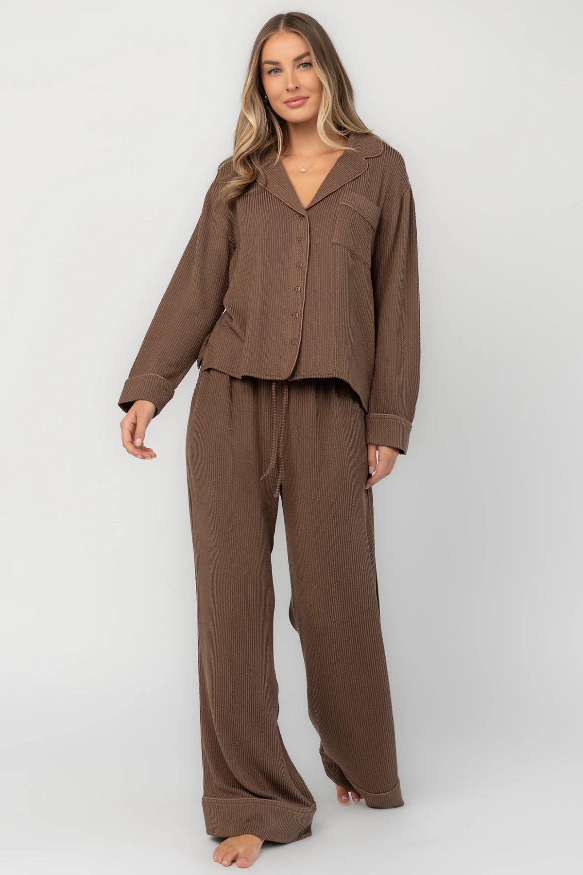 Brown ribbed pajama set with a button-front V-neck top, long sleeves, chest pocket, and wide-leg pants with an elastic drawstring waist.