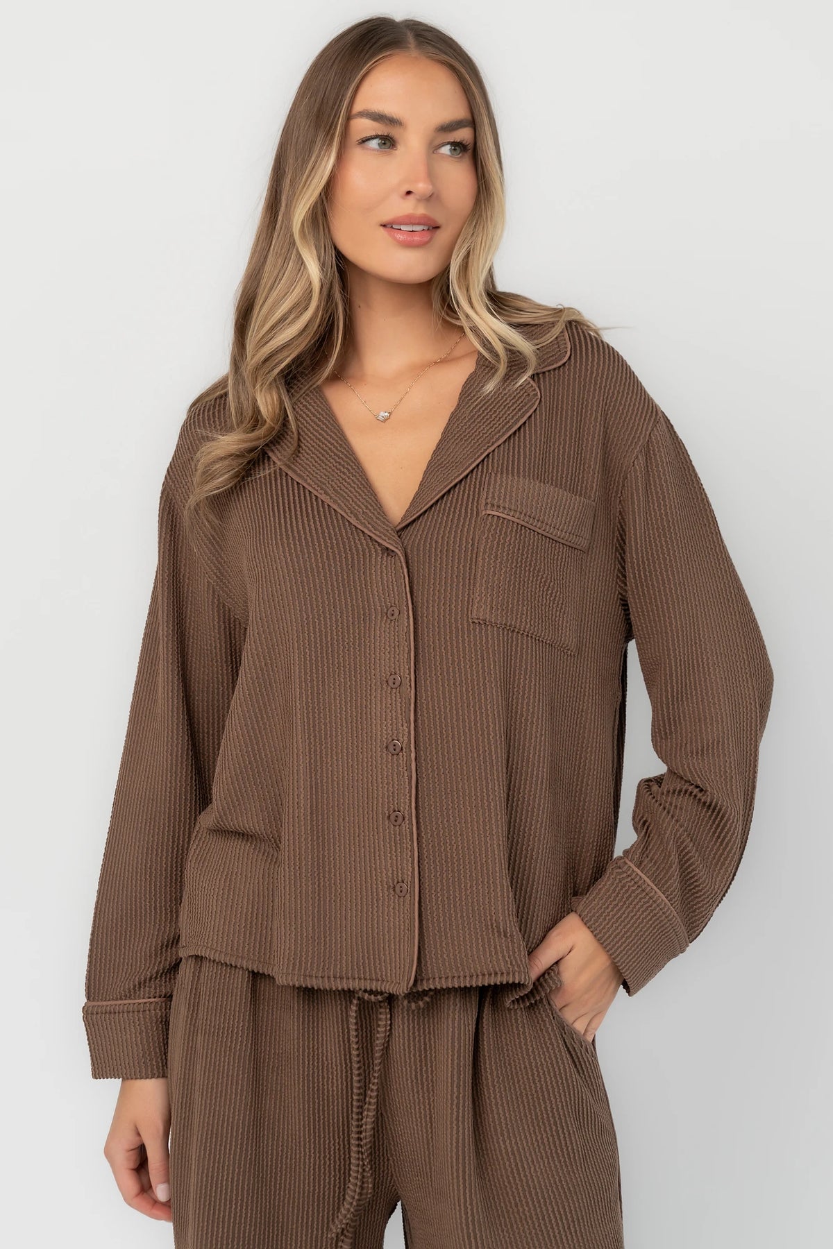 Brown ribbed pajama set with a button-front V-neck top, long sleeves, chest pocket, and wide-leg pants with an elastic drawstring waist.