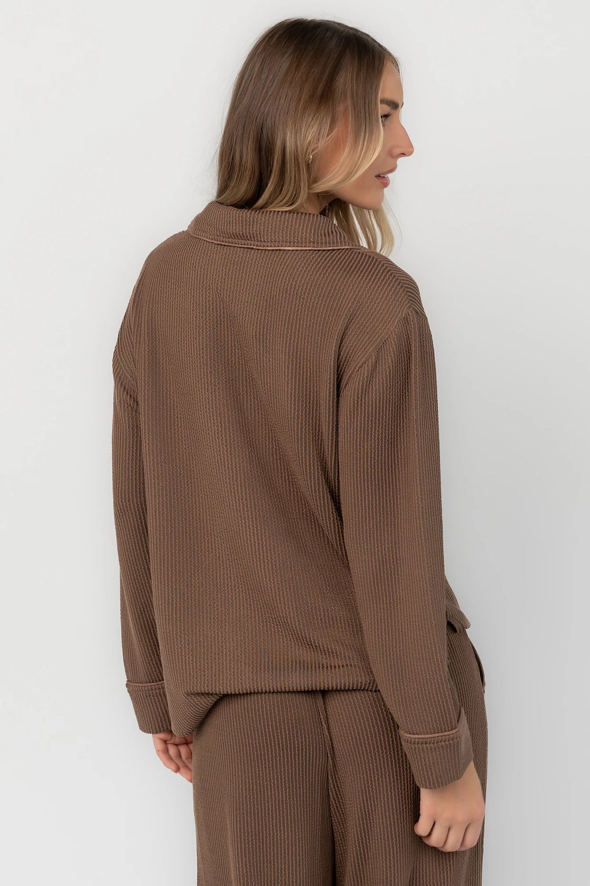 Brown ribbed pajama set with a button-front V-neck top, long sleeves, chest pocket, and wide-leg pants with an elastic drawstring waist.