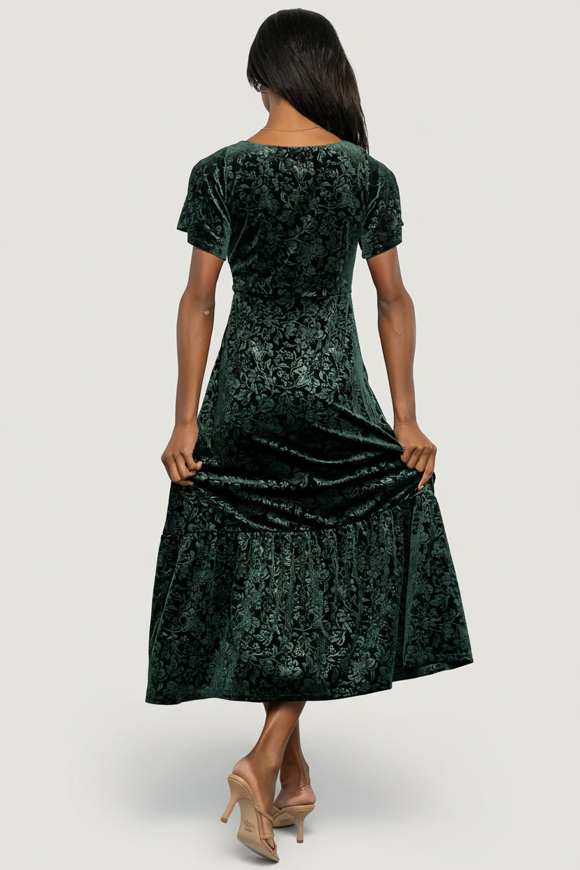 Model walking in Eirene emerald burnout velvet maxi dress, illustrating skirt movement, flutter sleeves, and overall fit.