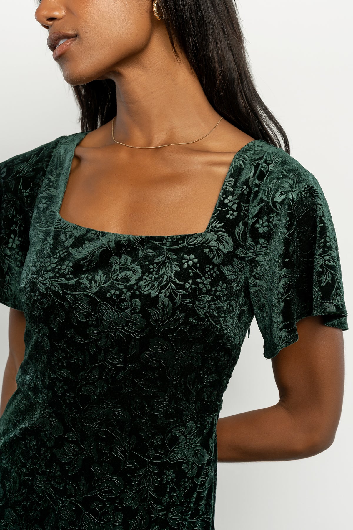 Back view of Eirene burnout velvet maxi dress in emerald, showing seam lines, tiered skirt, and gentle drape.