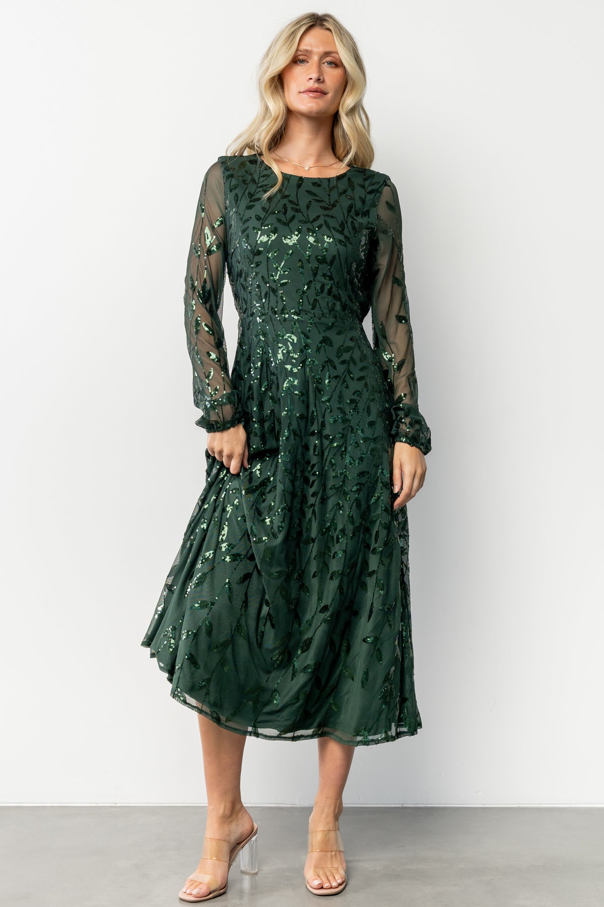 Front view of emerald Kalla sequin midi dress on model, showing A-line silhouette and long sheer sleeves with elastic cuffs.